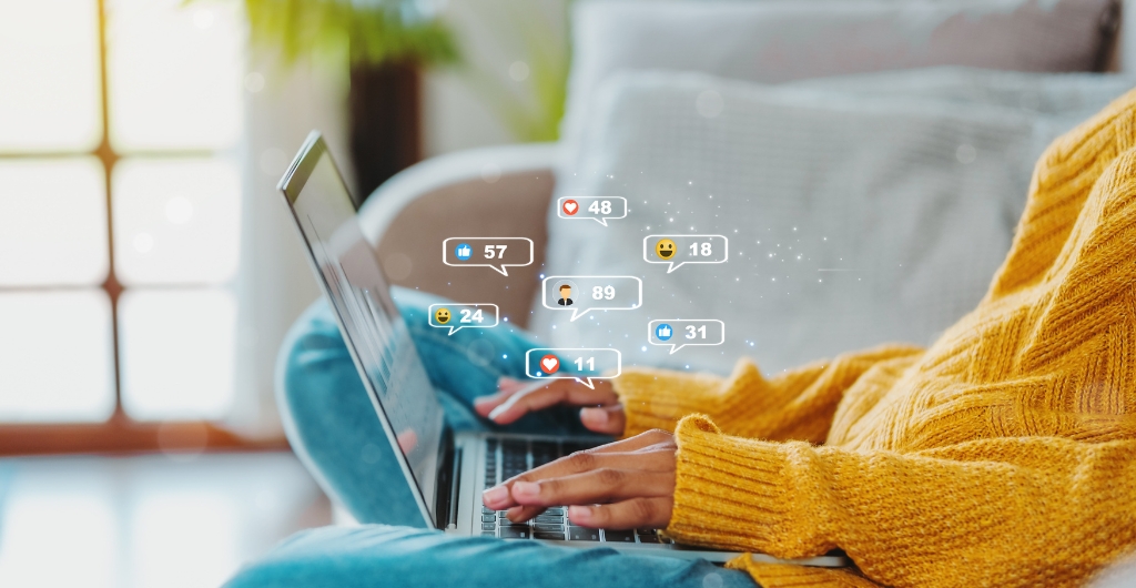 Woman sitting on a cough with a laptop in her lap and social media icons around it